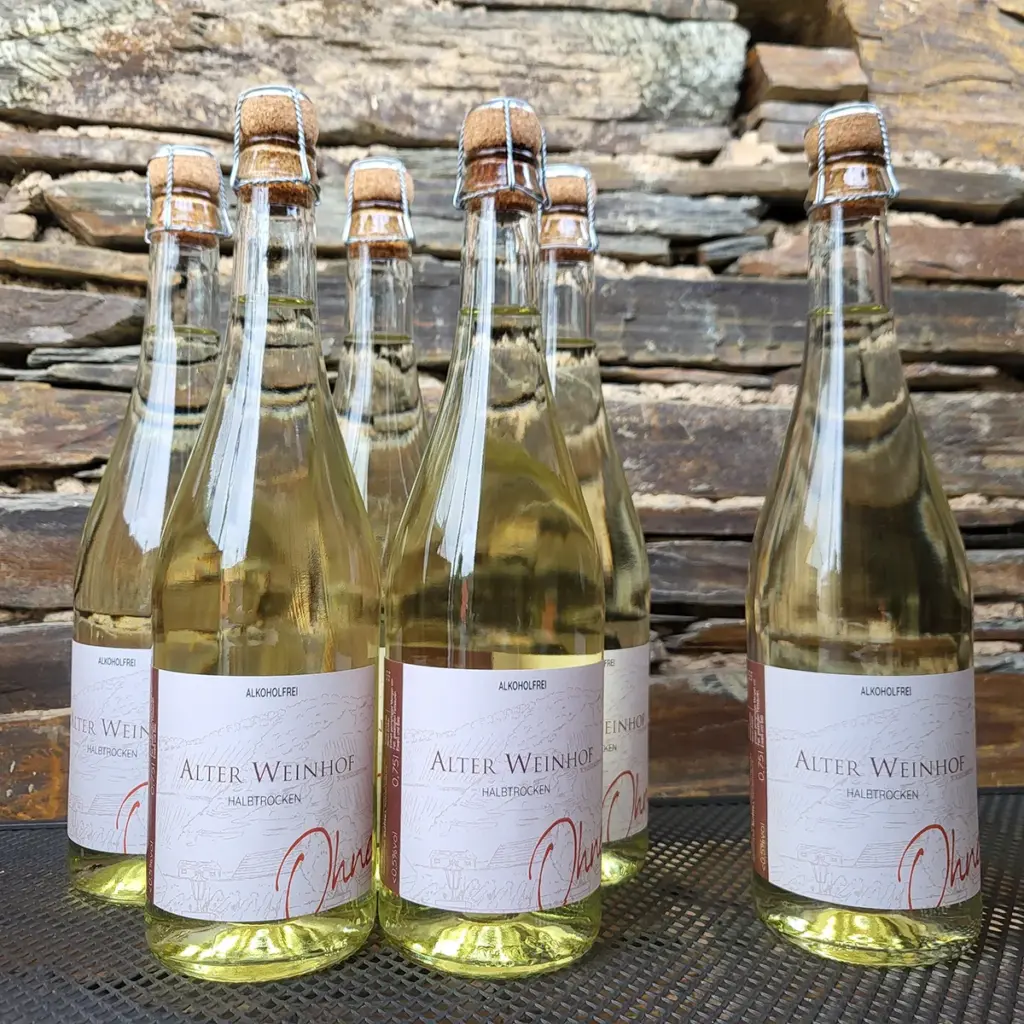 Fünf transparente Weinflaschen mit Etikett "Alter Weinhof - Alkoholfrei halbtrocken"